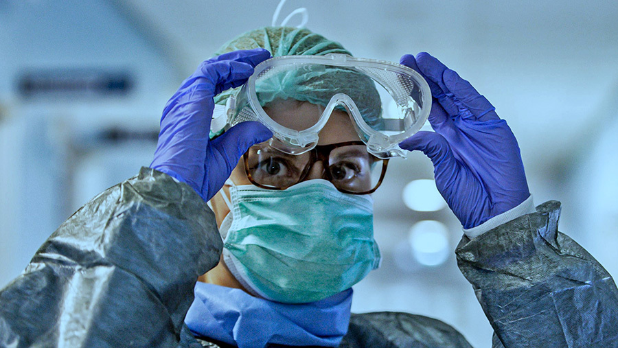 A medical worker wearing glasses and full PPE